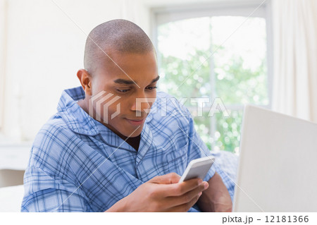 Happy man using laptop on bed and texting Happy man using laptop on bed and texting 12181366