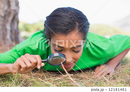 Pretty environmental activist looking at grass through magnifyin 12181461