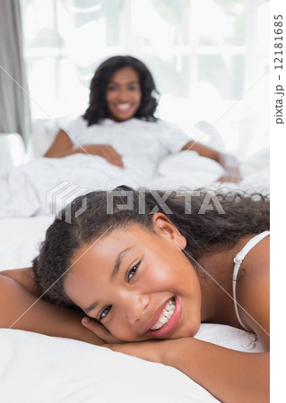 Happy mother and daughter relaxing on bed together 12181685
