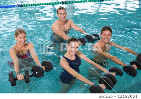 Happy fitness class doing aqua aerobics with foam dumbbells Happy fitness class doing aqua aerobics with foam dumbbells 12182061