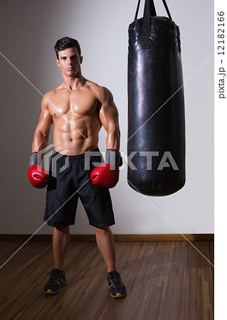 Shirtless muscular boxer with punching bag in gym 12182166