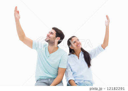 Cute couple sitting with arms raised Cute couple sitting with arms raised 12182291