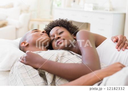 Happy couple lying in bed together Happy couple lying in bed together 12182332