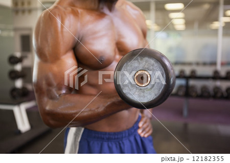 Muscular man exercising with dumbbell in gym Muscular man exercising with dumbbell in gym 12182355
