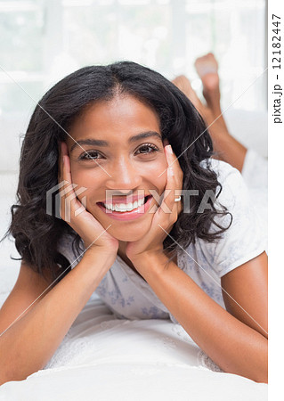 Pretty woman smiling at camera lying on bed 12182447