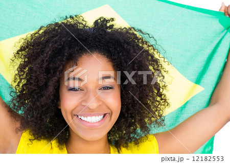 Pretty girl in yellow tshirt holding brazilian flag smiling at c 12182553
