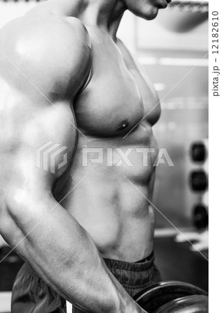 Mid section of shirtless muscular man exercising with dumbbell Mid section of shirtless muscular man exercising with dumbbell 12182610
