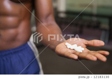 Muscular man holding vitamin pills in hand Muscular man holding vitamin pills in hand 12183130