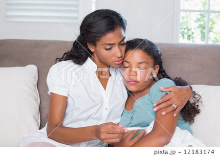 Concerned mother taking her daughters temperature 12183174