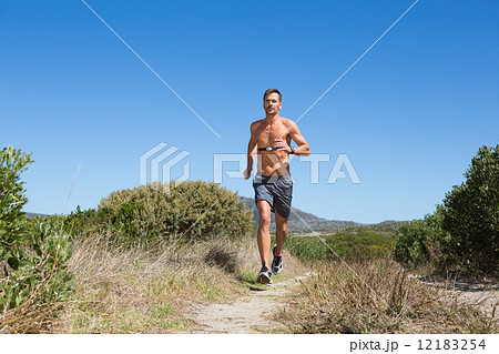 Shirtless man jogging with heart rate monitor around chest 12183254