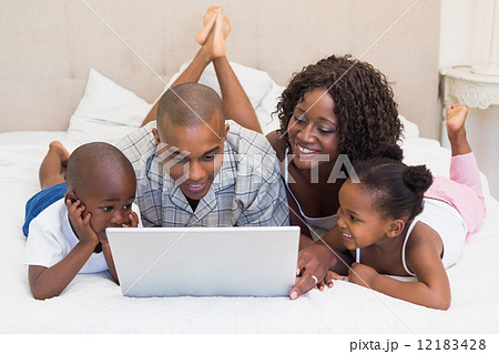 Happy family using laptop together on bed Happy family using laptop together on bed 12183428