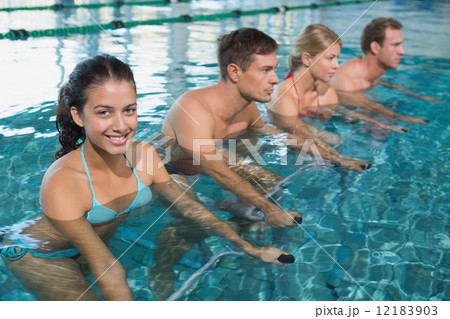 Fitness class doing aqua aerobics on exercise bikes 12183903