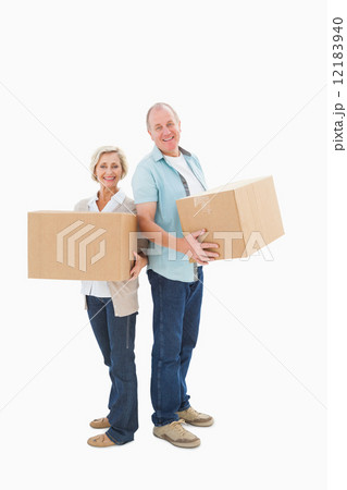 Older couple smiling at camera holding moving boxes Older couple smiling at camera holding moving boxes 12183940