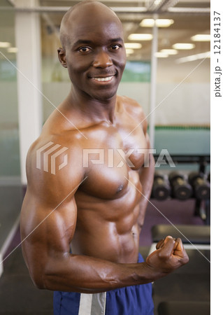 Smiling shirtless muscular man posing in gym 12184137