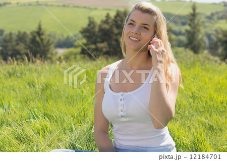 Pretty blonde on the phone sitting on grass Pretty blonde on the phone sitting on grass 12184701