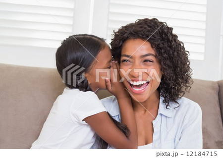 Pretty mother sitting on the couch with her daughter whispering Pretty mother sitting on the couch with her daughter whispering 12184715