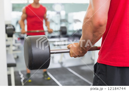 Muscular man lifting barbell in gym 12184744