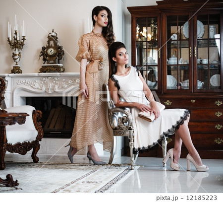 Two young women near fireplace in luxury house interior Two young women near fireplace in luxury house interior 12185223