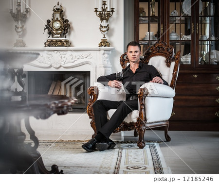 Handsome well-dressed man sitting with red wine in luxury house interior Handsome well-dressed man sitting with red wine in luxury house interior 12185246