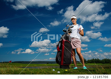 Young cheerful woman with bag and bottle of water on a golf field Young cheerful woman with bag and bottle of water on a golf field 12185766