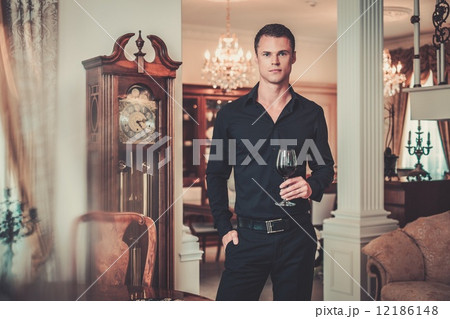 Handsome young well-dressed man in luxury house interior with glass of red wine 12186148