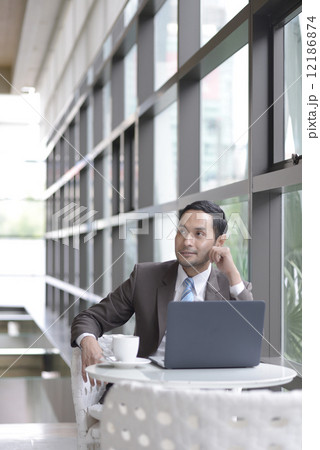 Asian businessman drinking coffee in lobby Asian businessman drinking coffee in lobby 12186874