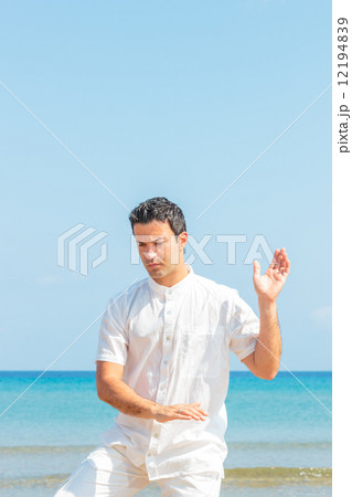 Handsome man on the beach meditating Handsome man on the beach meditating 12194839