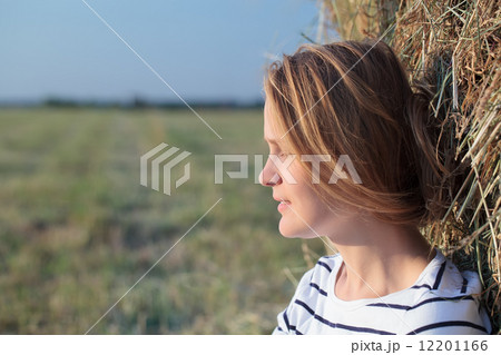 Relaxed woman near hay roll in the field 12201166