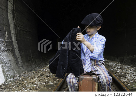 Child in vintage clothes sits on railway road 12222044