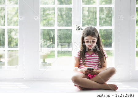 A girl sitting playing, holding a smart phone. A girl sitting playing, holding a smart phone. 12222993
