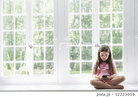 A girl sitting playing, holding a smart phone. A girl sitting playing, holding a smart phone. 12223009
