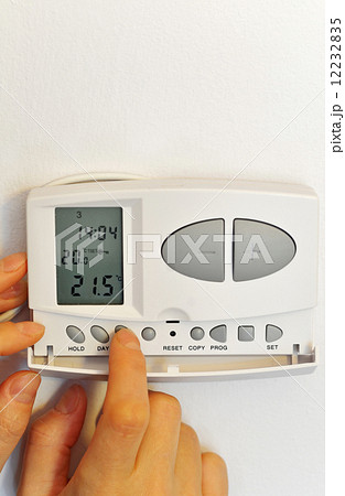 hand pressing button on digital thermostat 12232835