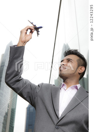 Portrait of Asian business executive holding toy plane 12243295