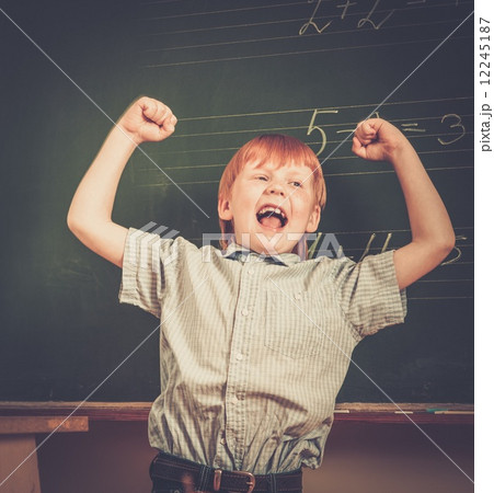 Little funny redhead schoolboy near blackboard 12245187