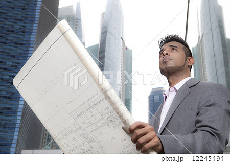 Asian business executive looking at architectural plans outdoors 12245494