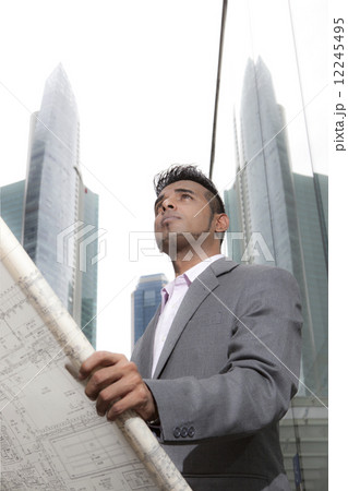 Asian business executive looking at architectural plans outdoors Asian business executive looking at architectural plans outdoors 12245495
