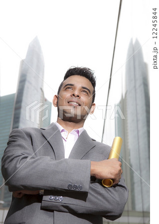 Asian businessman holding gold baton outdoors 12245844