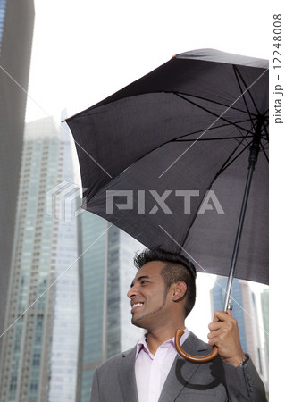 Businessman holding up umbrella outdoors  12248008