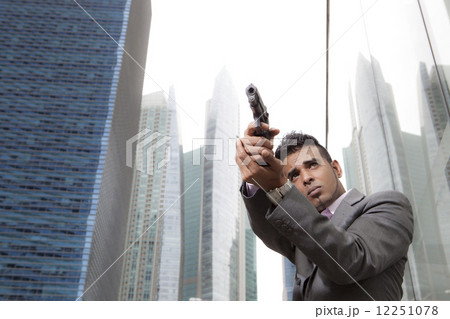Businessman holding gun outdoors 12251078
