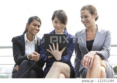 Businesswomen looking at tablet outside Businesswomen looking at tablet outside 12251194