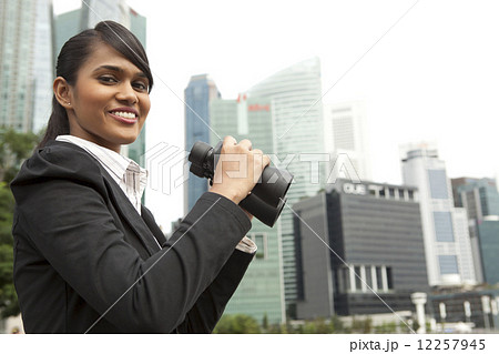 Businesswoman holding binoculars outdoors 12257945