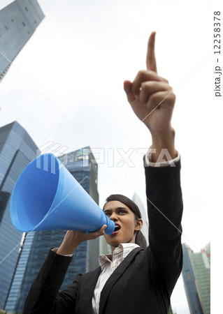Businesswoman using loud hailer outside 12258378