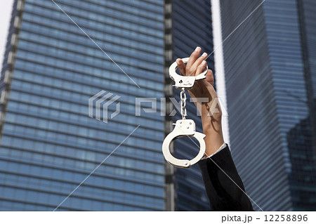 Hands holding up handcuffs outside Hands holding up handcuffs outside 12258896