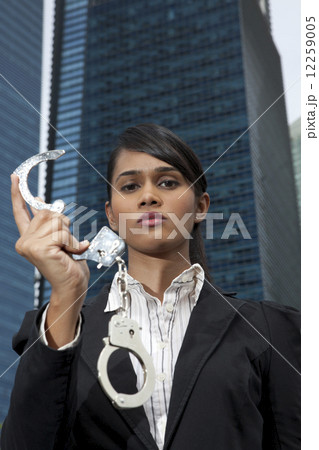 Business woman holding handcuffs outside  12259005