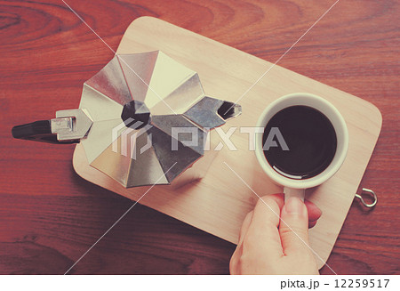 Hand holding coffee cup and moka pot with retro filter effect Hand holding coffee cup and moka pot with retro filter effect 12259517