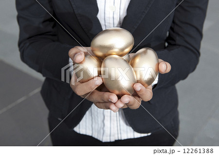 close-up of hands holding gold eggs outdoors close-up of hands holding gold eggs outdoors 12261388