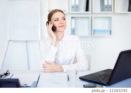 beautiful young business woman sitting at office desk and talkin 12263292