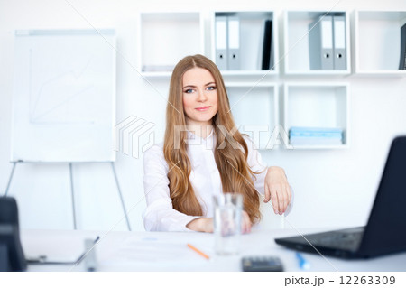 Portrait of beautiful young smiling business woman sitting at d Portrait of beautiful young smiling business woman sitting at d 12263309