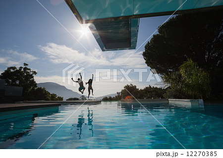 Cheerful young couple jumping into swimming pool Cheerful young couple jumping into swimming pool 12270385