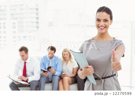 Businesswoman gesturing thumbs up against people waiting for interview Businesswoman gesturing thumbs up against people waiting for interview 12270599